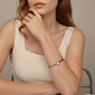Krémszínű felsőt viselő modell karján látható elegáns ezüst szív karkötő