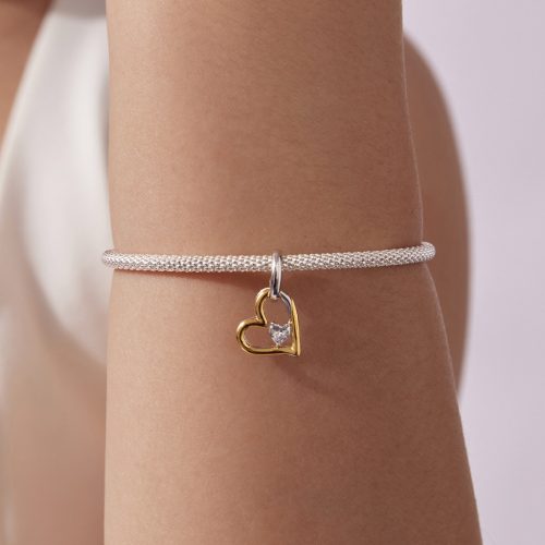 Ezüst mesh karkötő két tónusú szív charm függővel, női csuklón viselve.