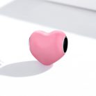 Minimalista, lágy rózsaszín tónusú ezüst szív charm finom vetett árnyékkal, letisztult stúdiókörnyezetben fotózva.