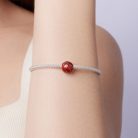 Viselés közben fotózott, minimalista ezüst karkötő egyedi kosárlabda alakú ékszer charmmal.