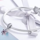 Elegáns fehér masnis ajándékdoboz tetején elhelyezett ezüst kígyólánc karkötő csillogó, rózsaszín virág alakú függő charm díszítéssel.