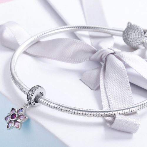 Elegáns fehér masnis ajándékdoboz tetején elhelyezett ezüst kígyólánc karkötő csillogó, rózsaszín virág alakú függő charm díszítéssel.